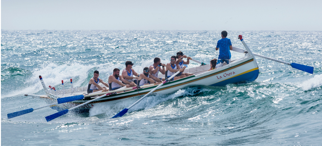 Photographie d'un bateau avec des rameurs franchissant une vague