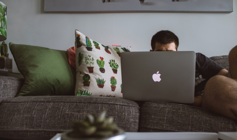 Photographie d'un homme en train de regarder un ordinateur sur un canapé