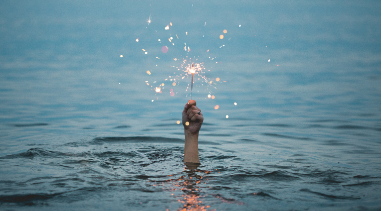 Photographie d'une main au dessus de l'eau