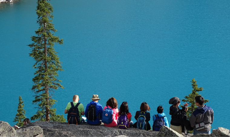 Photographie d'une famille assise de dos face à un lac