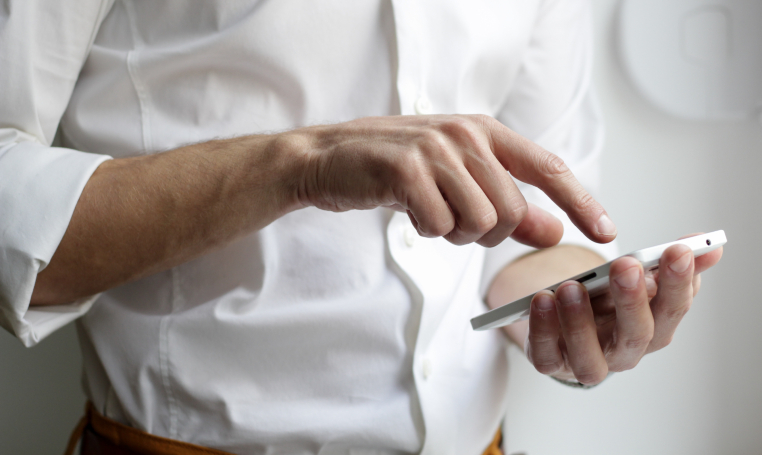 Photographie d'un homme appuyant sur son téléphone portable