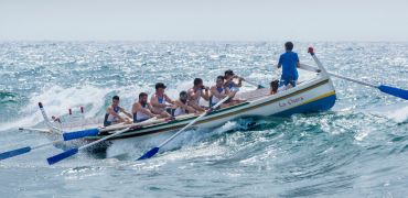 Photographie d'un bateau avec des rameurs franchissant une vague