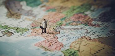 Photographie d'une carte du monde avec dessus un homme levant la main
