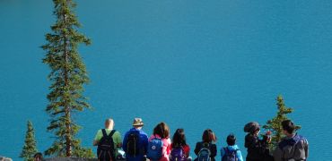 Photographie d'une famille assise de dos face à un lac